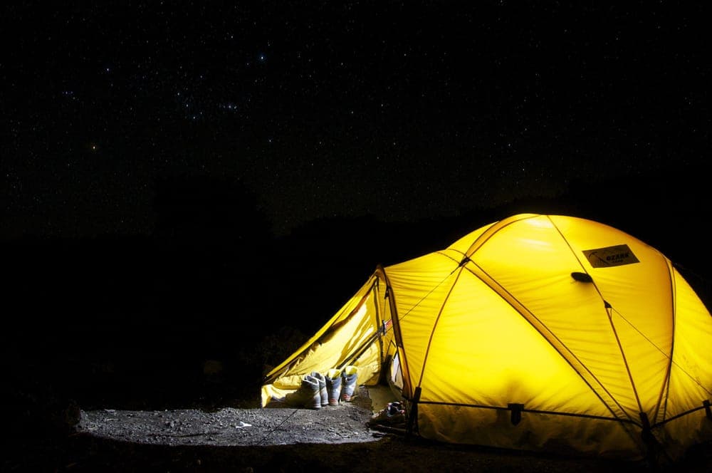 A glowing tent under a star-filled night sky