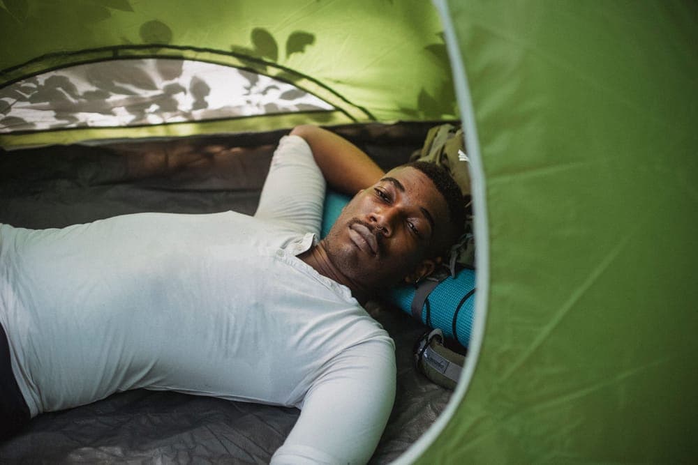 A hiker lying in a tent with a hand behind his head