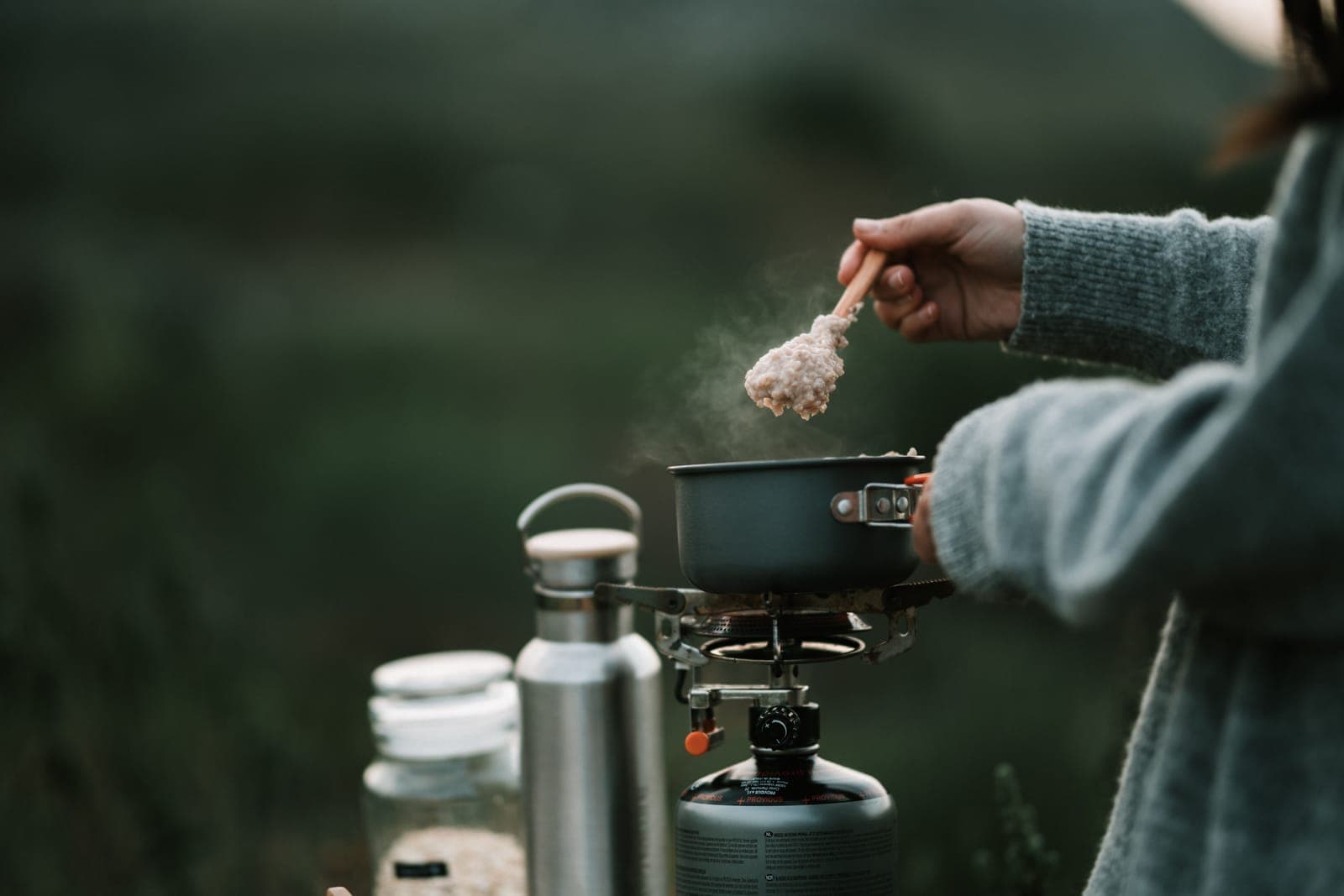 Oatmeal steaming in a pot on a small portable stove at camp